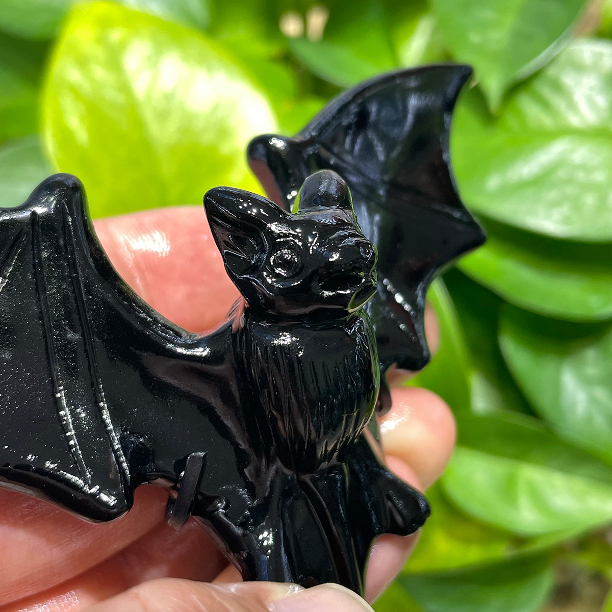 Closeup of the detailed face and body of a black obsidian bat figurine.