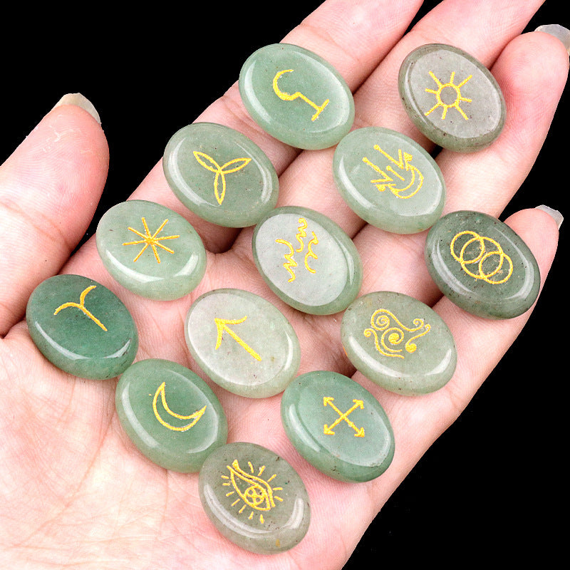 Hand holding green stones with yellow symbols on a black background