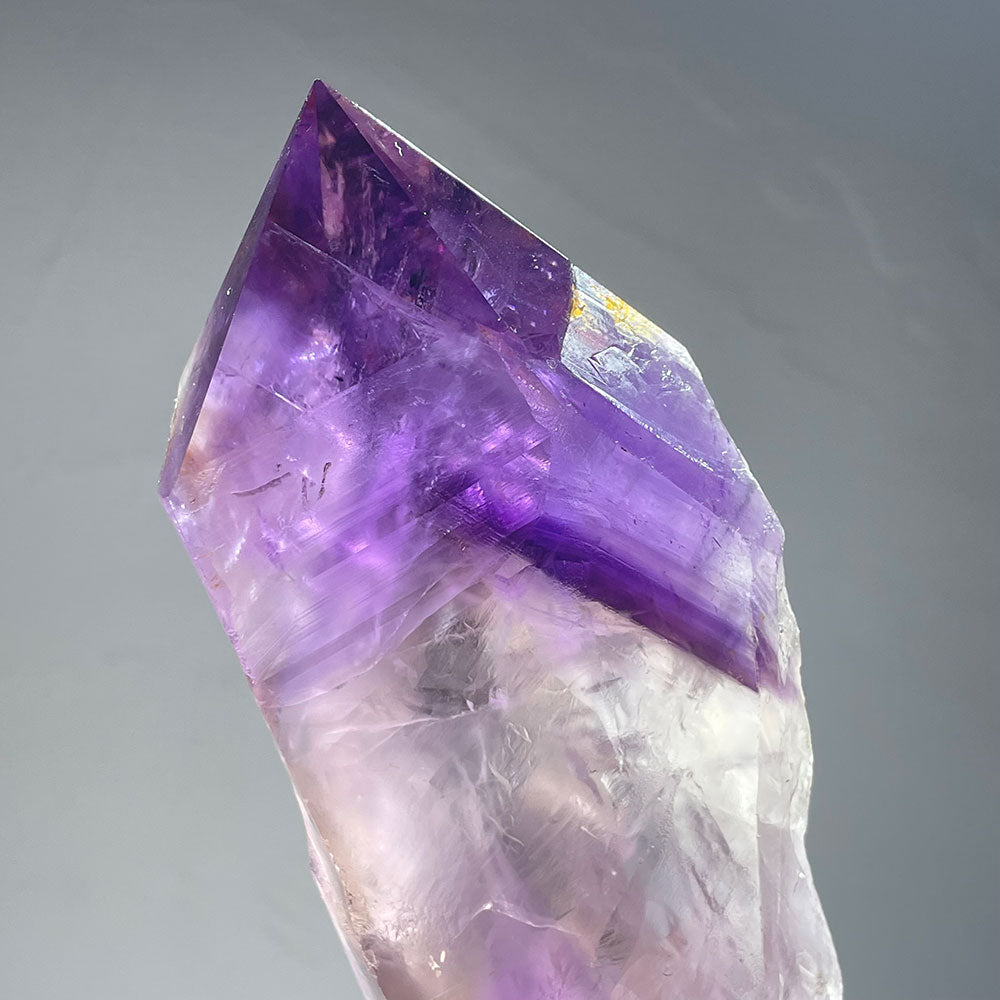 Detailed view of the polished faces and vibrant purple phantoms inside an amethyst scepter