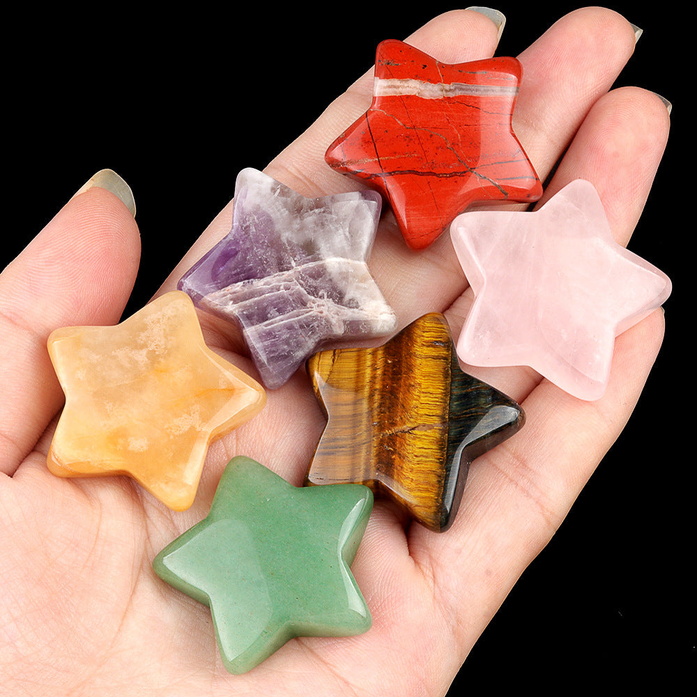 Hand holding seven assorted polished crystal stars, including amethyst, rose quartz, and tiger's eye