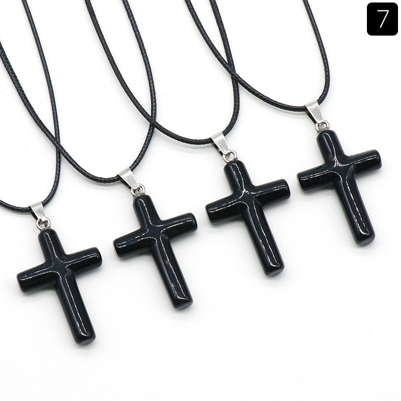 Four black obsidian cross necklaces with black cords laid out on a white background