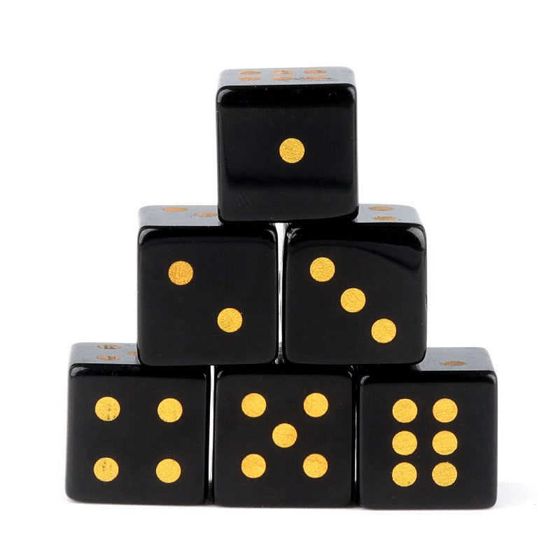 A set of six black obsidian dice with gold pips stacked in a pyramid.