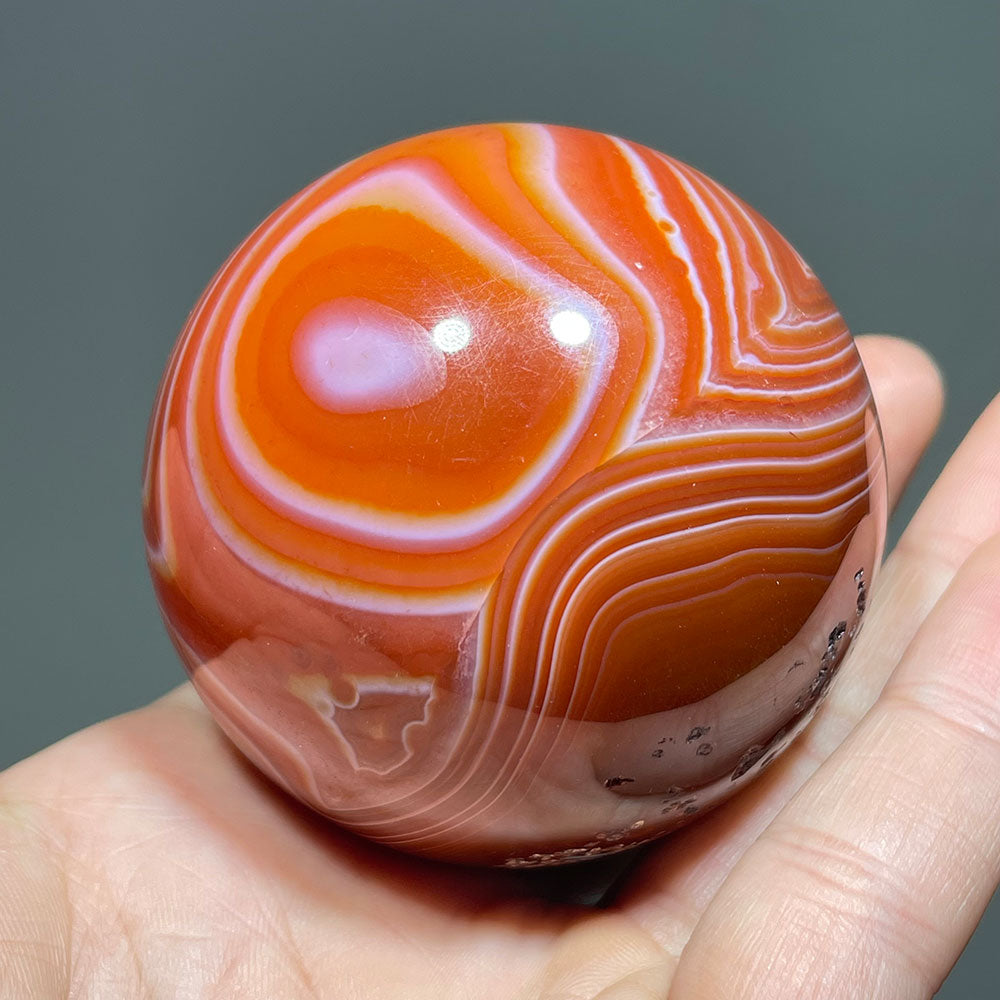 A polished red agate sphere showing its beautiful concentric white bands