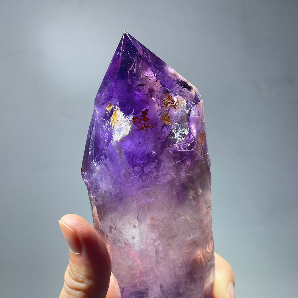 Closeup of the gemmy, deep purple tip of a large amethyst scepter with golden inclusions.