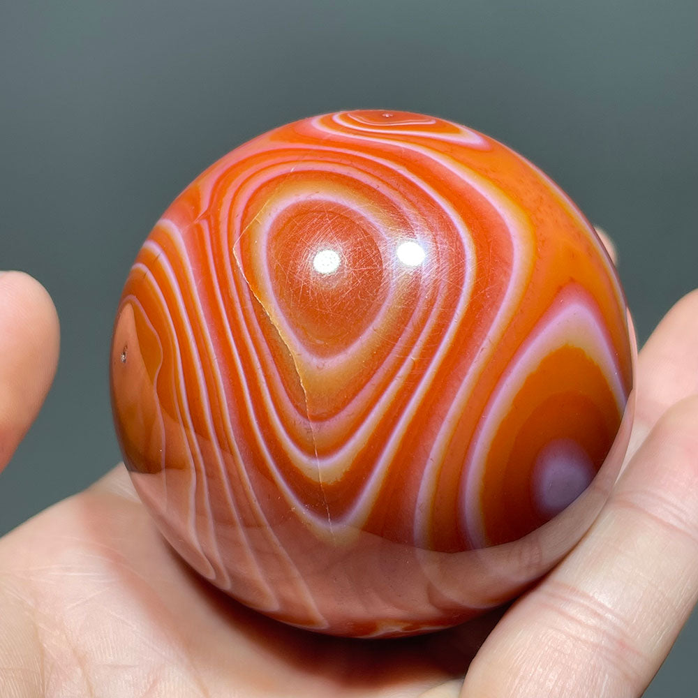 Side view of a vibrant orange and red banded carnelian agate crystal ball