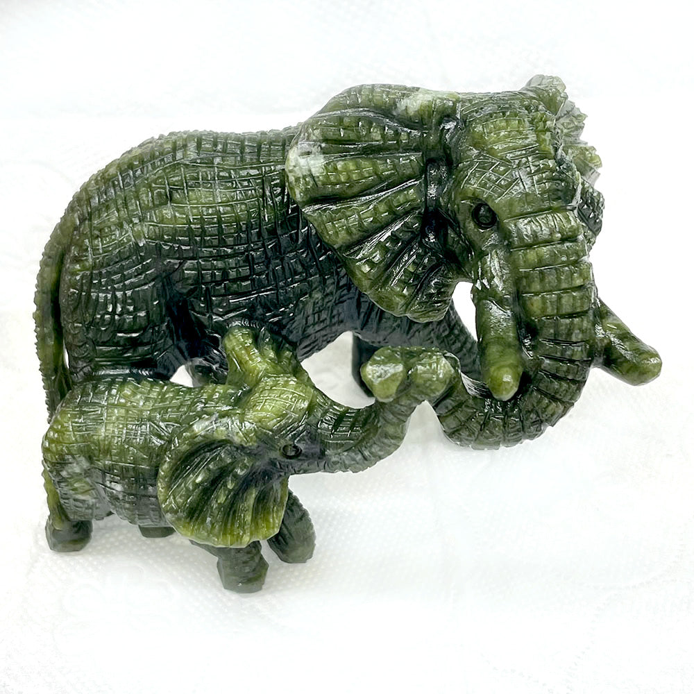 A green serpentine carving with detailed texture, depicting a mother elephant and her calf