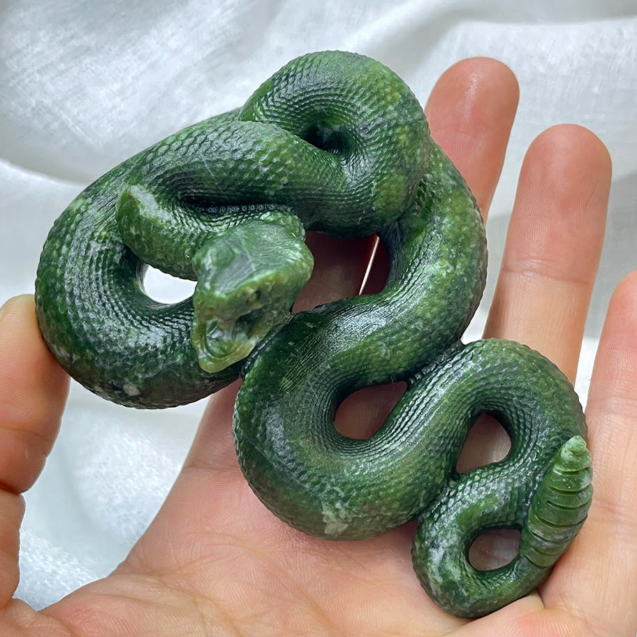Top-down view of a coiled green serpentine snake carving with detailed scales, held in hand