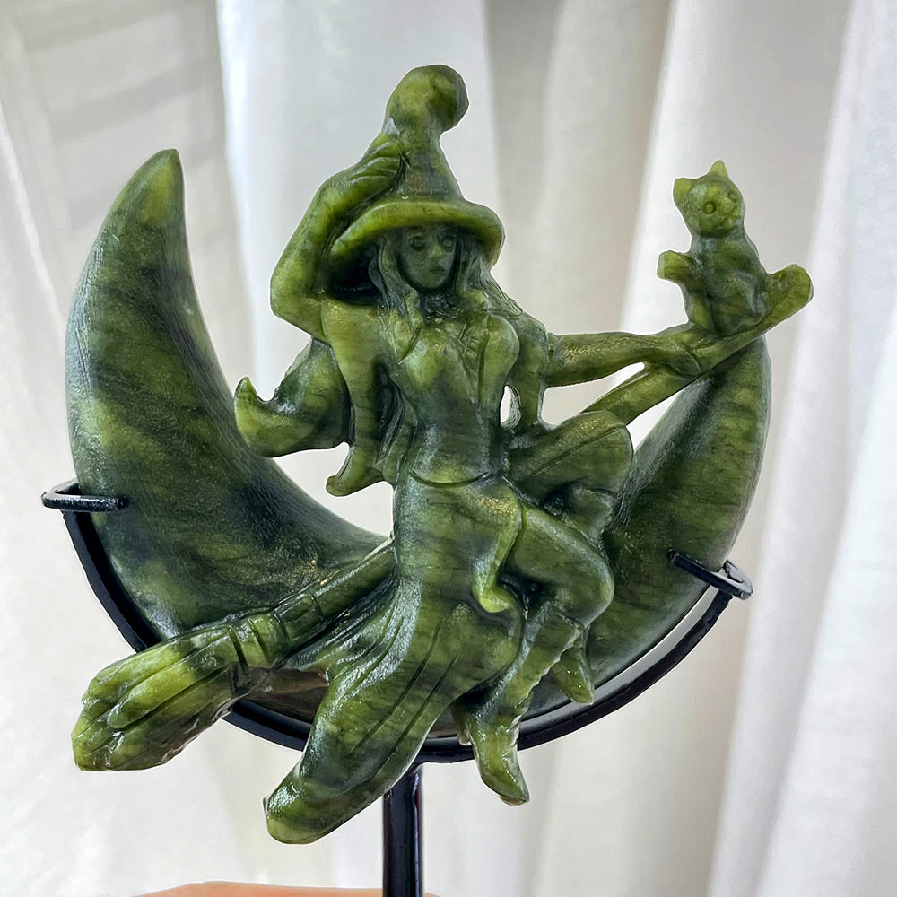 A green Serpentine statue of a witch on a crescent moon with her cat familiar