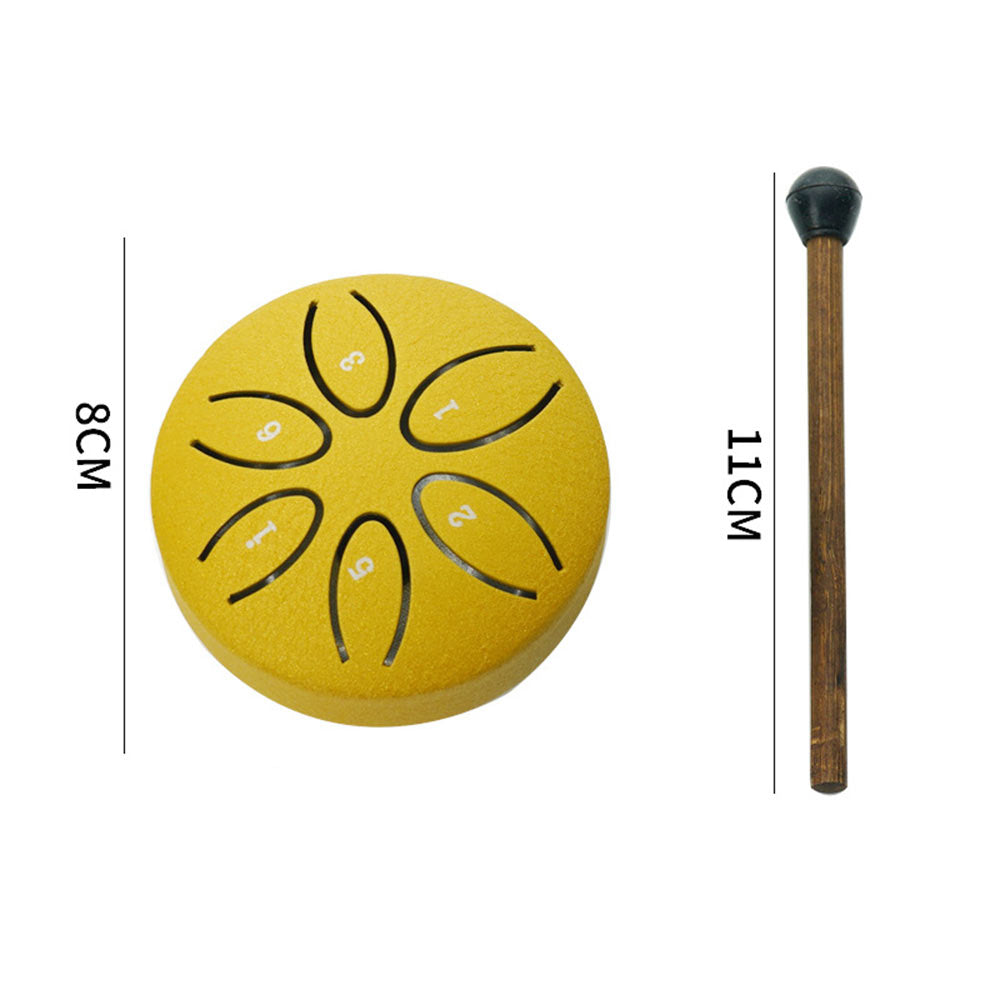 A small mallet striking a yellow mini steel tongue drum, used for meditation and sound healing