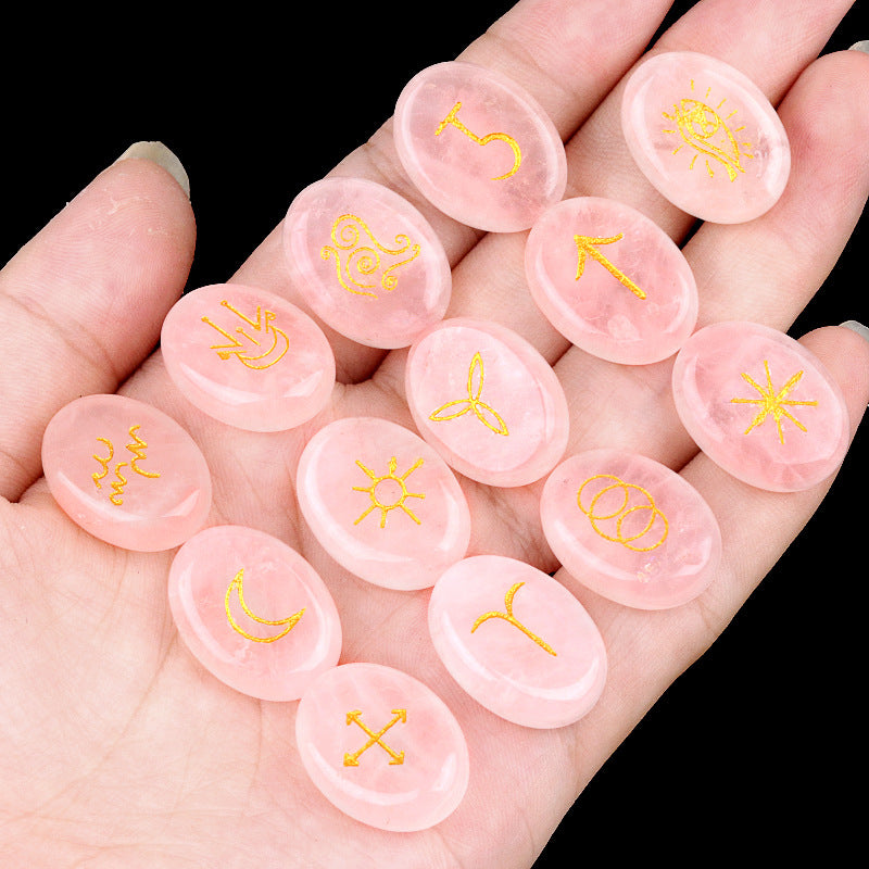 Pink stones with yellow symbols held in a hand against a black background