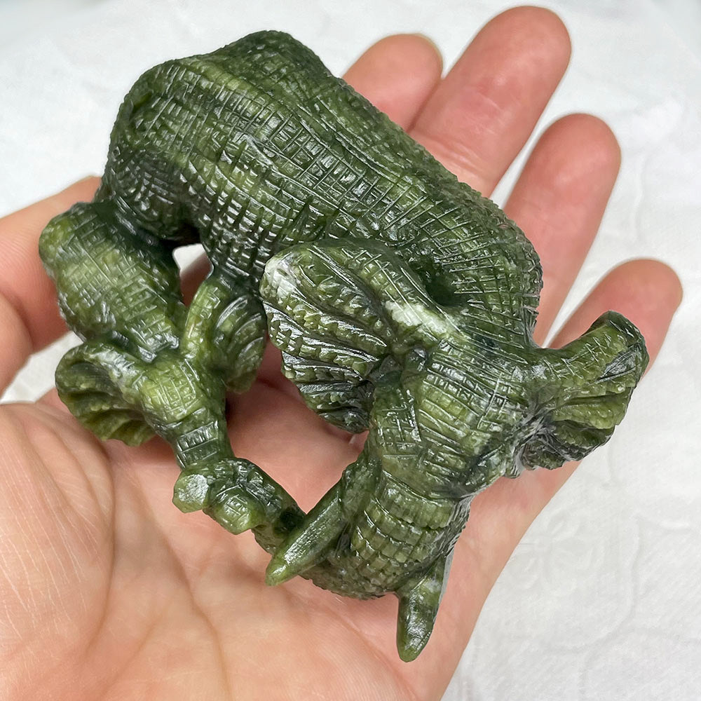 Hand holding a green serpentine elephant statue to show its size and intricate carving detail