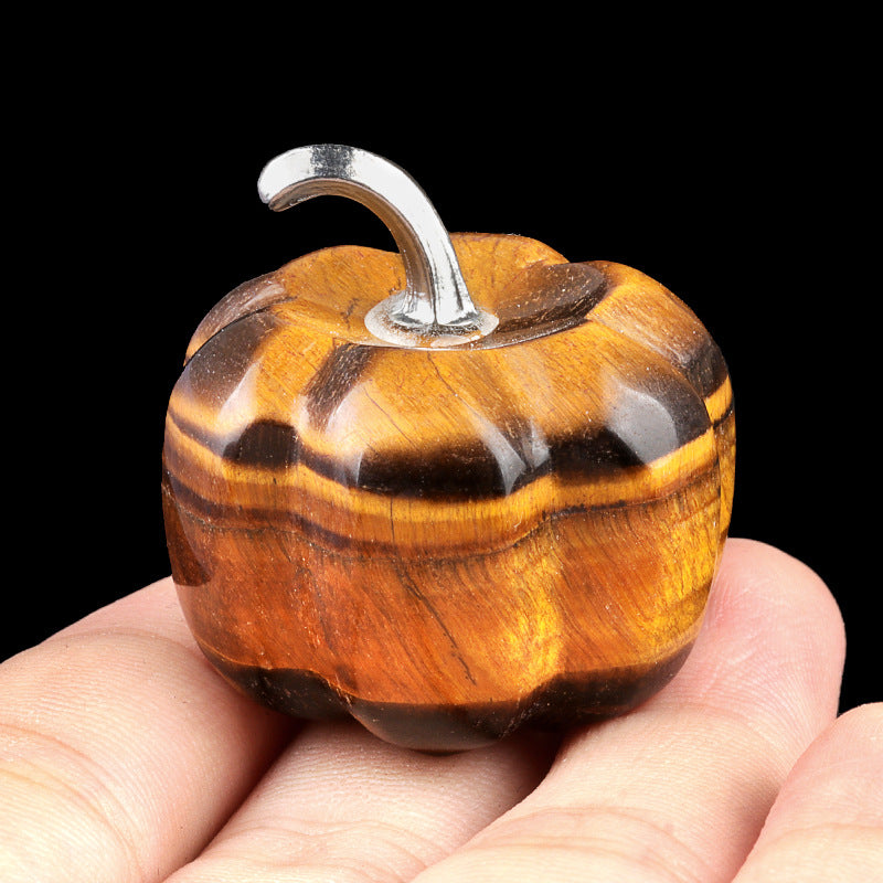 A polished tiger's eye crystal pumpkin showing its golden chatoyancy and a silver stem