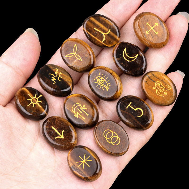Hand holding a collection of stones with engraved symbols against a black background