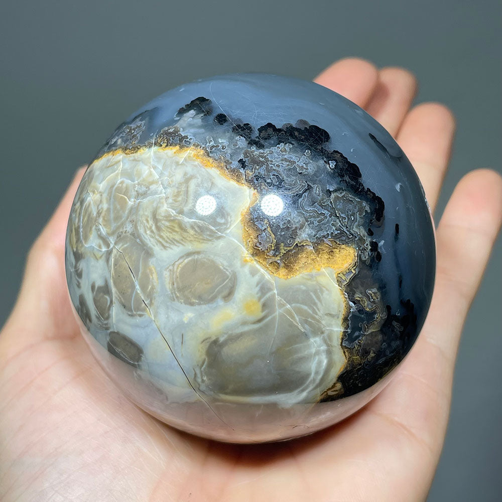 The botryoidal and scenic patterned side of a large volcanic agate crystal ball