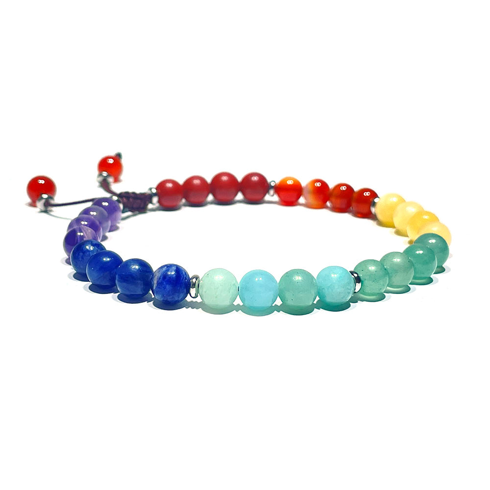An adjustable 7 chakra bracelet with a macrame knot and red bead tassels