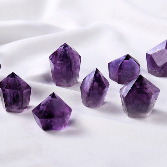 Several small, polished amethyst crystal points on a white silk background.