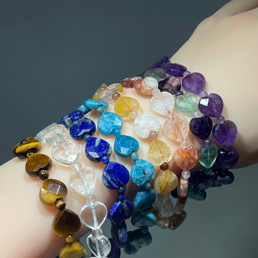 Multicolored crystal heart beaded bracelets on a hand against a dark background