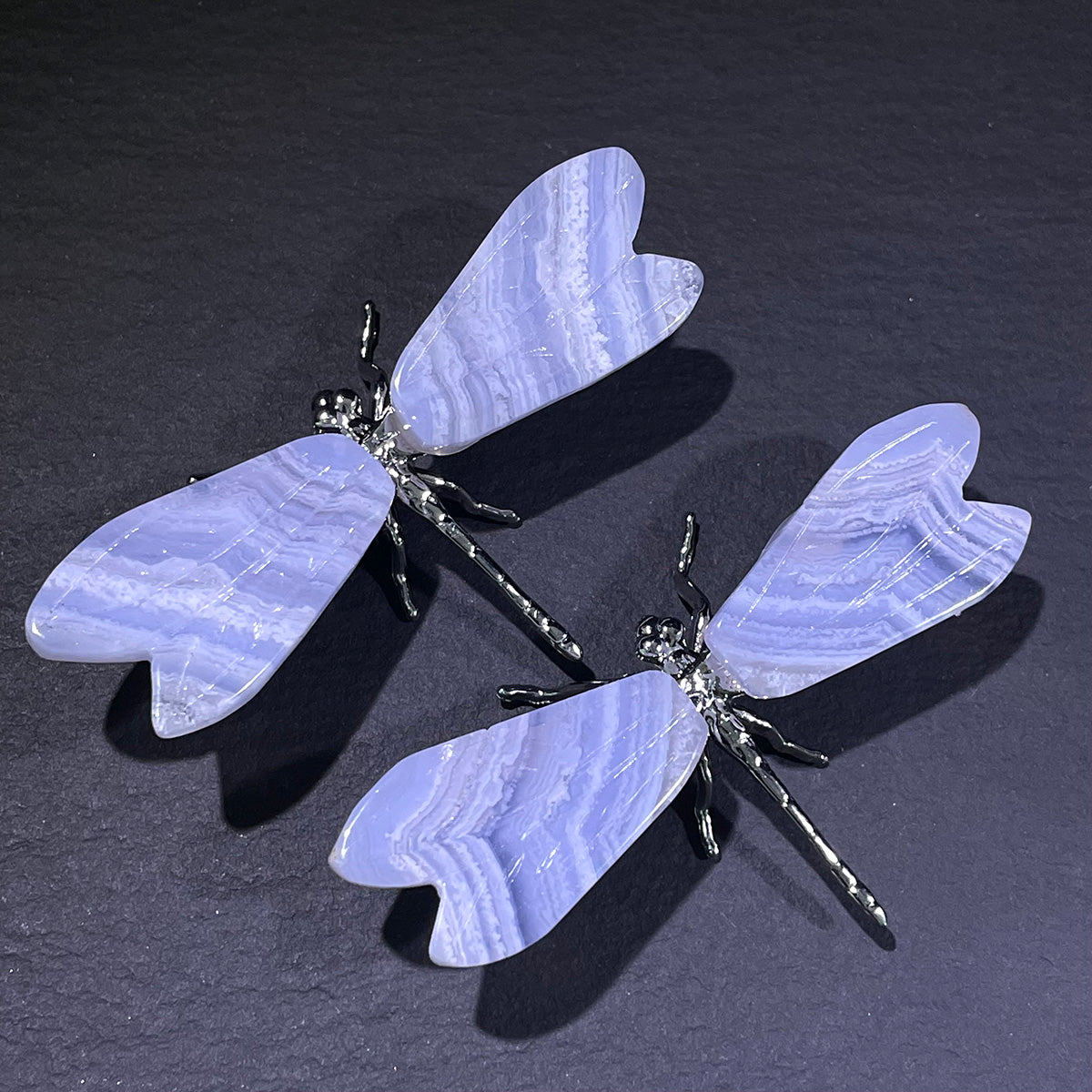 Dragonfly-shaped earrings with light purple wings on a dark background