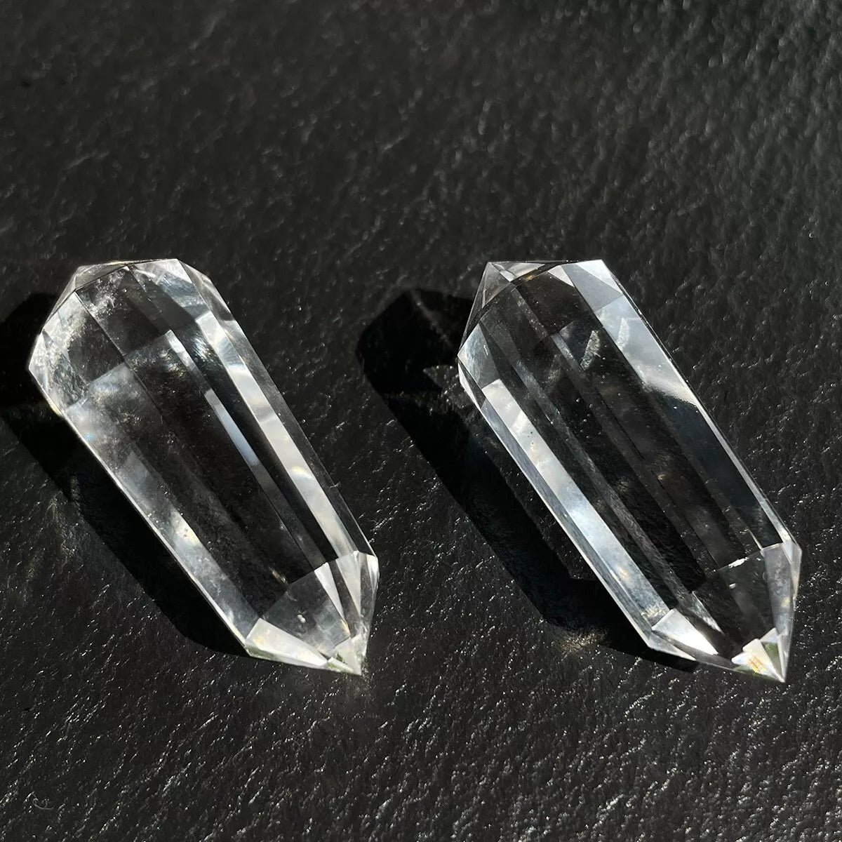 A pair of double-terminated clear quartz Vogel healing wands showing their facets.