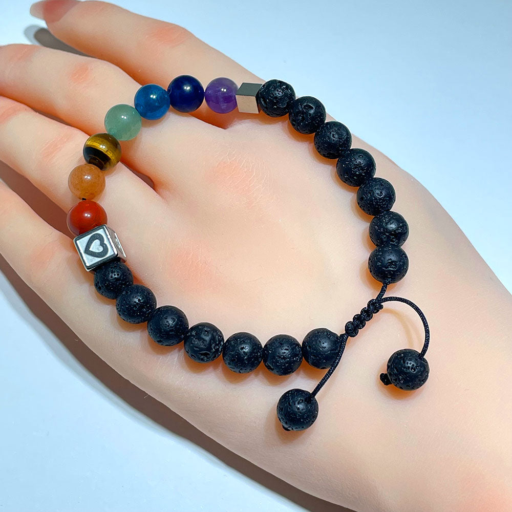 A person's wrist wearing the adjustable version of the 7 chakra lava stone bracelet