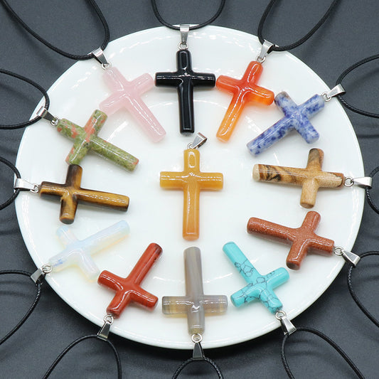 A collection of thirteen assorted crystal and gemstone cross pendants on a white plate
