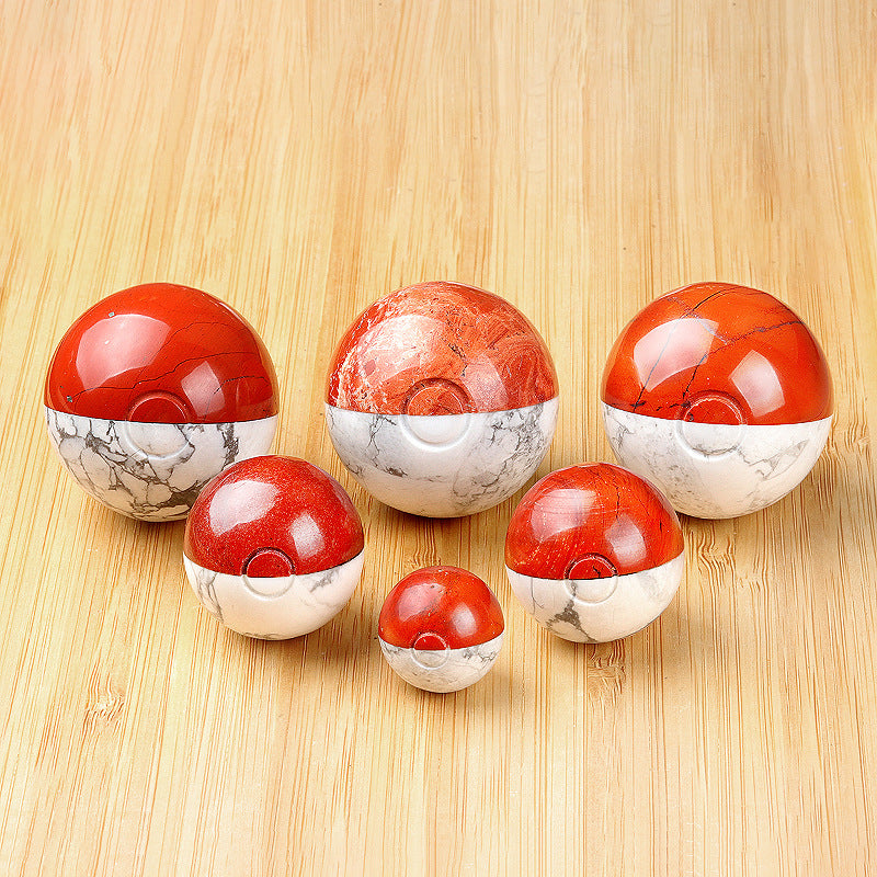 A collection of several red and white crystal "monster catcher" balls on a wooden surface