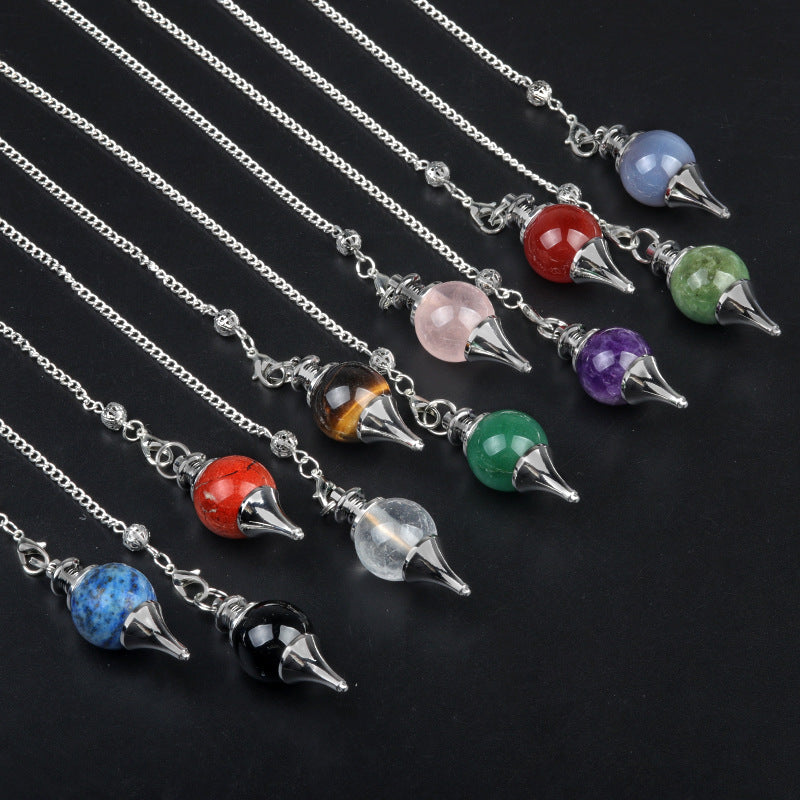 A collection of assorted crystal pendulums on a black background, including amethyst and tiger's eye.