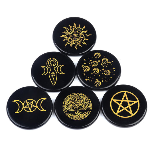 A collection of seven black obsidian discs engraved with various golden mystical symbols