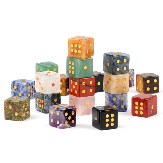 A pile of assorted, hand-carved crystal and gemstone dice on a white background
