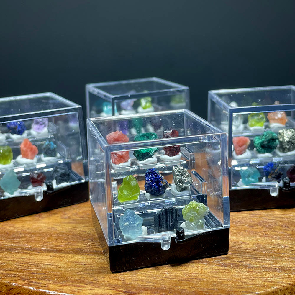 Four miniature crystal specimen boxes displayed on a wooden surface