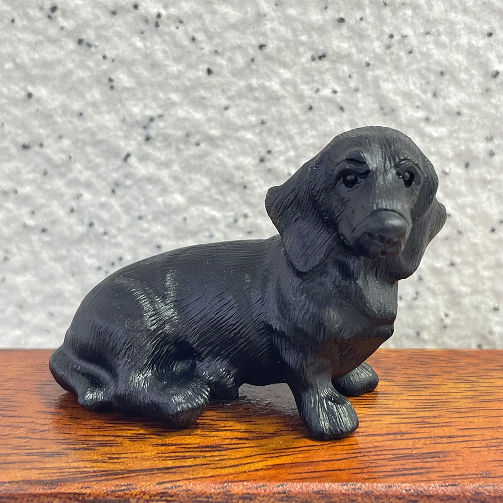 A side profile of a long-bodied, hand-carved black obsidian Dachshund figurine
