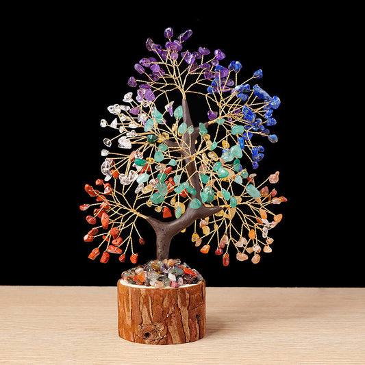 A handmade chakra crystal tree of life with seven different colored gemstones on a wood base