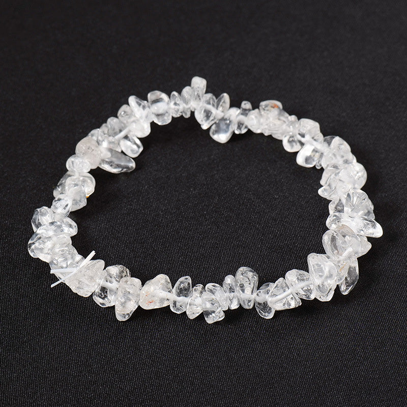 A stretchy bracelet made from raw clear quartz crystal chips on a black background