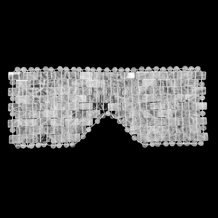 A hand-woven clear quartz crystal eye mask on a black background