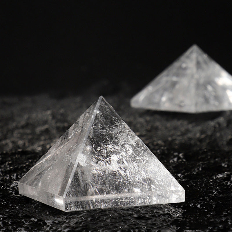 A close-up of a polished clear quartz pyramid showing its internal inclusions on a dark surface