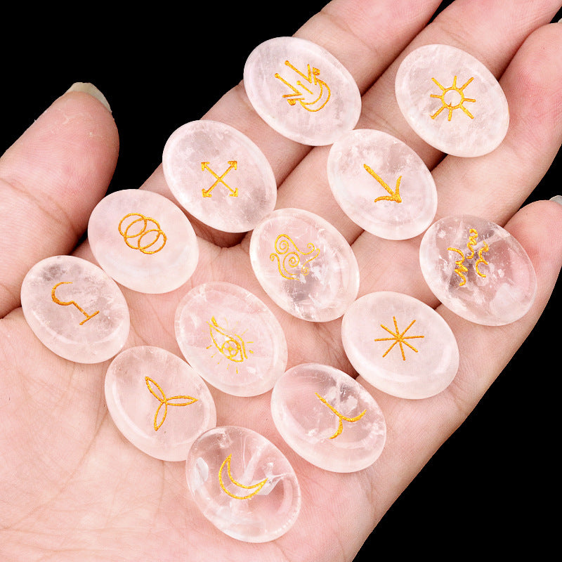 Clear stones with gold symbols held in a hand against a black background