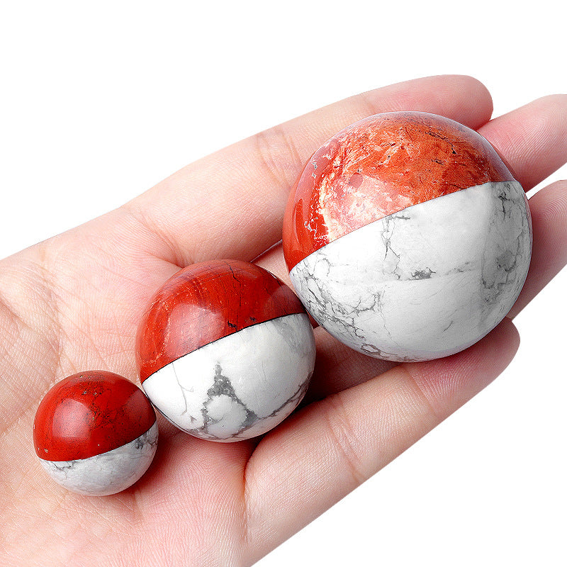 Hand holding three sizes of red and white crystal trainer spheres