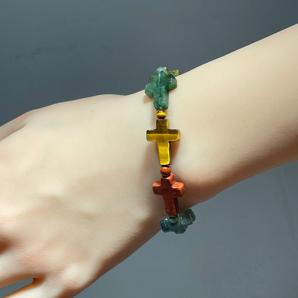 crystal cross beaded bracelet on a wrist against a neutral background