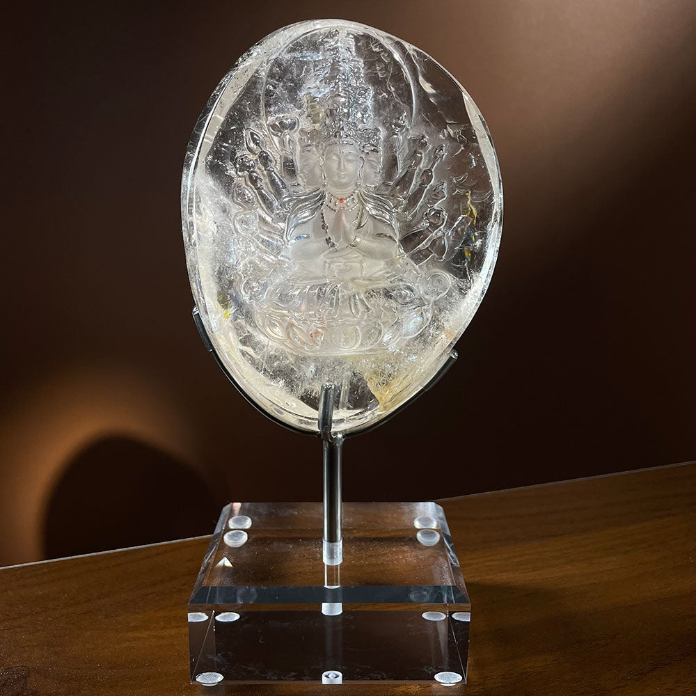 Master carved natural clear quartz Thousand Hand Guan Yin statue with internal rainbows resting on an acrylic display stand.