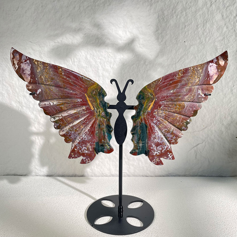 A large 280mm natural ocean jasper carved into butterfly wings, displaying vibrant red, green, and gold colors on a custom black metal stand.