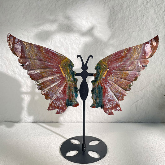 A large 280mm natural ocean jasper carved into butterfly wings, displaying vibrant red, green, and gold colors on a custom black metal stand.