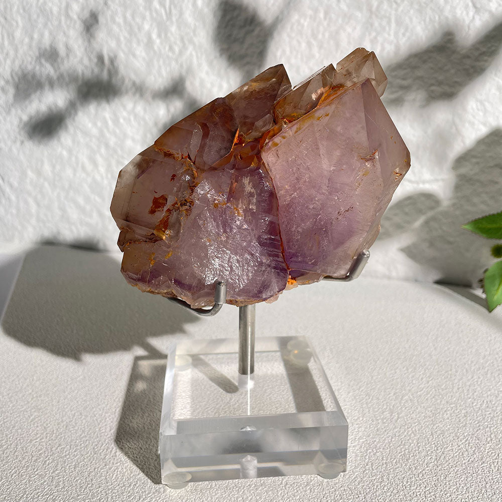 A large natural Madagascar Amethyst Elestial quartz cluster featuring deep purple hues and earthy iron inclusions, resting on a clear acrylic display stand.