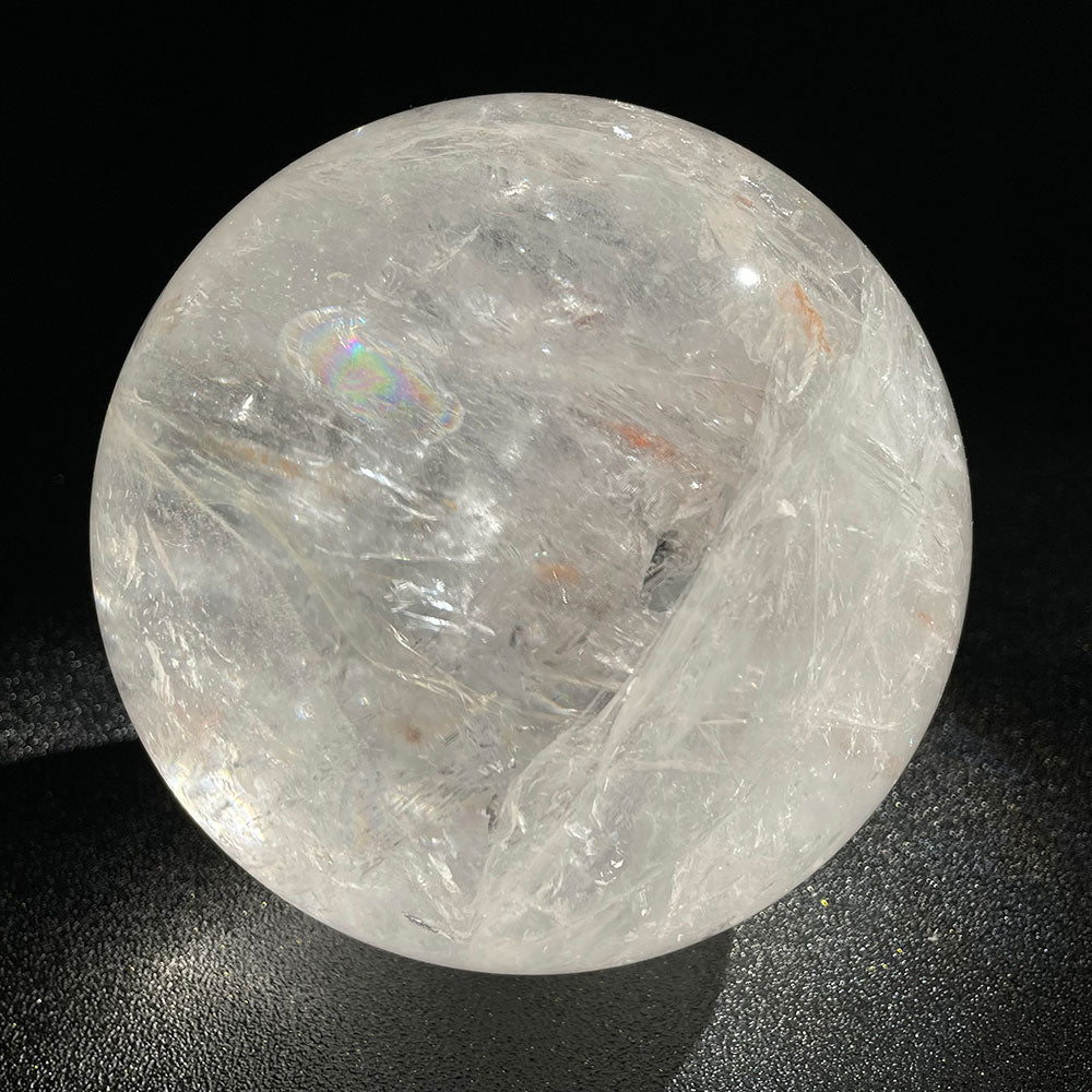 A massive 2.49kg highly transparent natural clear quartz crystal sphere displaying brilliant internal rainbow flashes against a dark background.