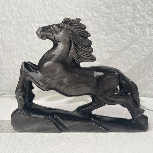 A large 1.95kg hand-carved silver sheen obsidian galloping horse statue displaying a beautiful metallic silver flash under direct light.