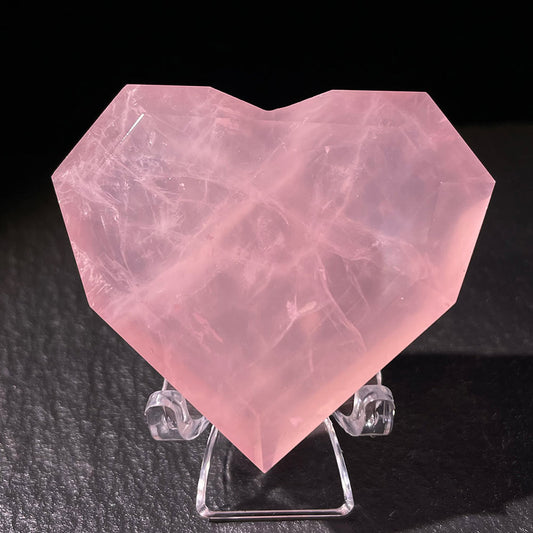 Front view of a faceted, gem-cut rose quartz heart on a display stand