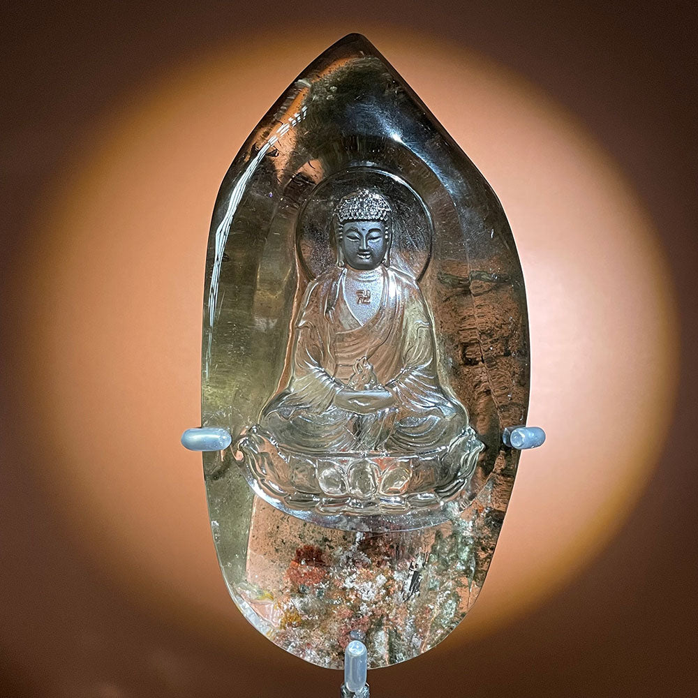 A massive 1.395kg natural garden quartz crystal featuring a frosted meditating Buddha carving hovering over a multi-colored scenic phantom landscape.