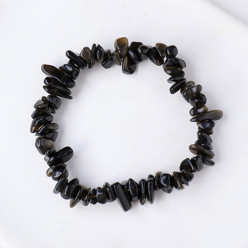 A stretchy bracelet made from raw golden sheen obsidian chips showing a subtle flash