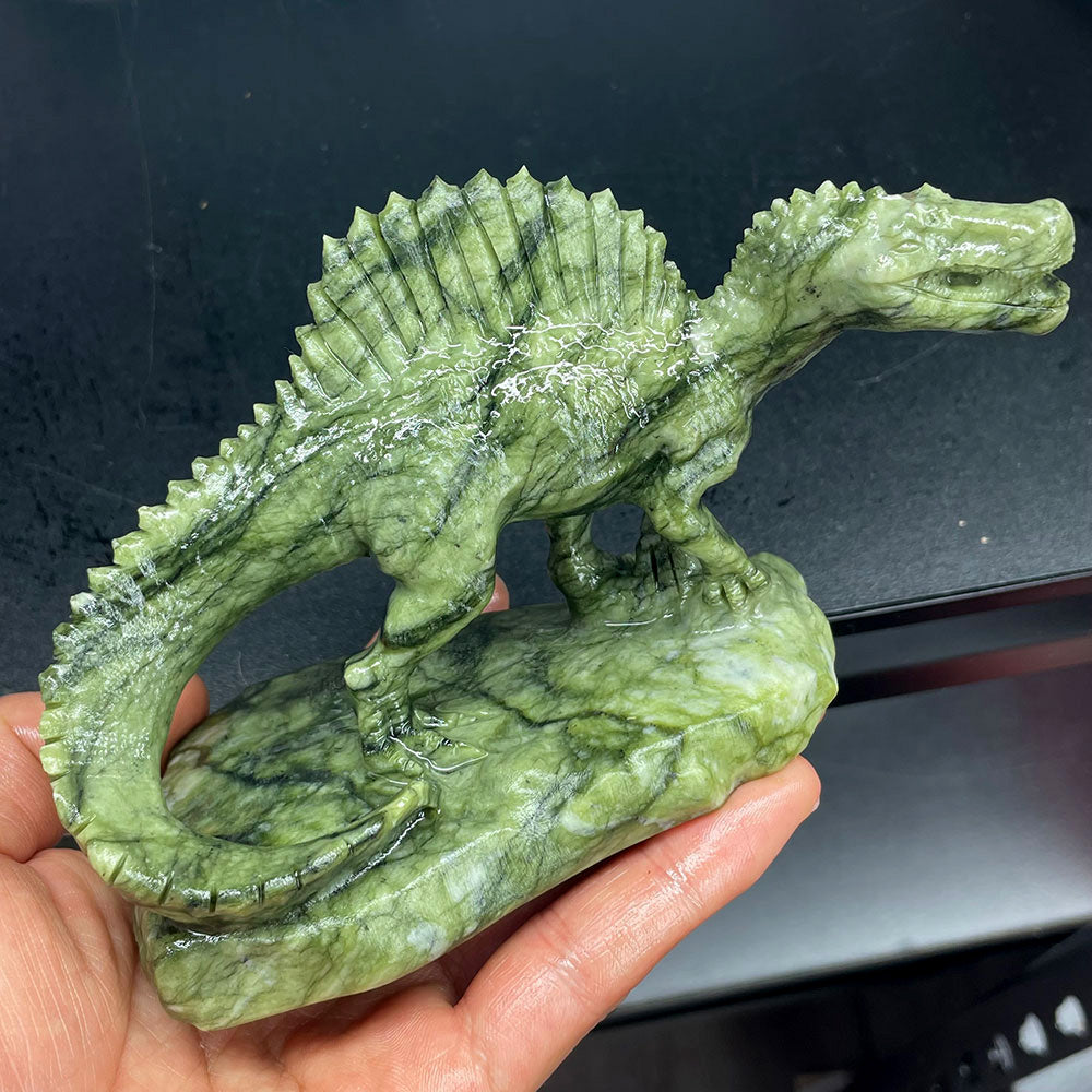 Side profile of a hand-carved green Serpentine stone Spinosaurus showing detailed sail and tail texture