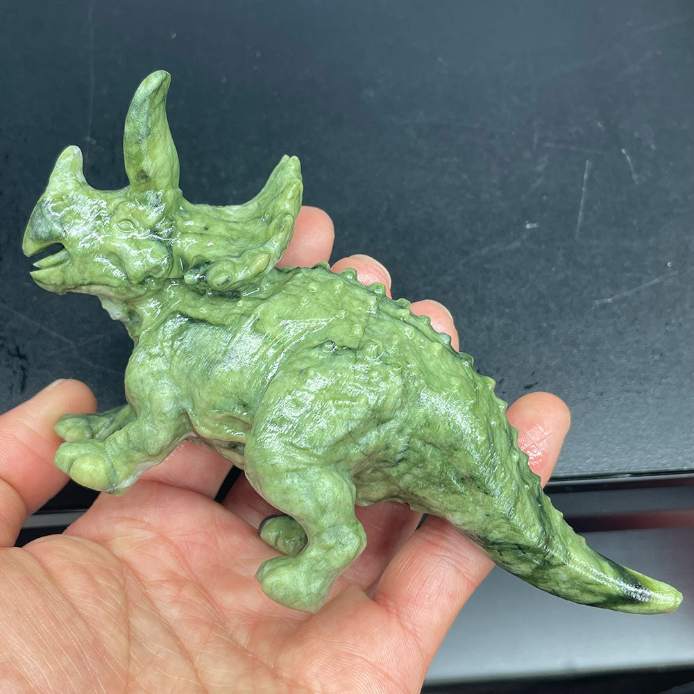 Hand holding a green Serpentine crystal triceratops carving showing detailed scale texture and side profile