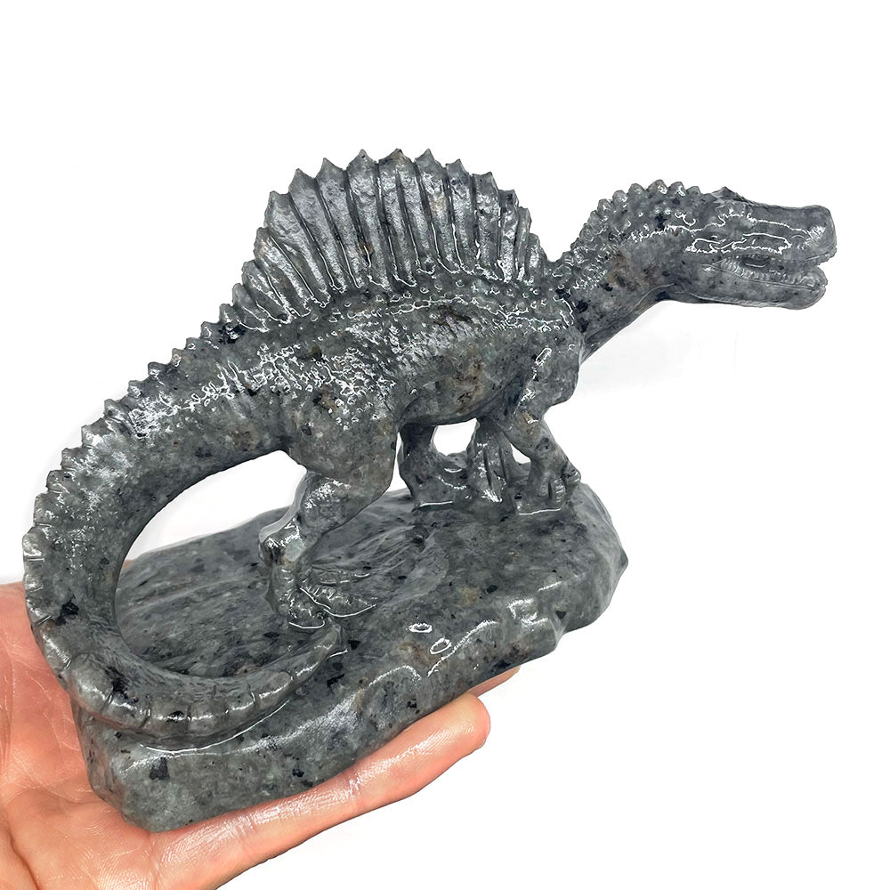 Grey Yooperlite crystal Spinosaurus figurine standing on a stone base, showcasing the natural mineral pattern.